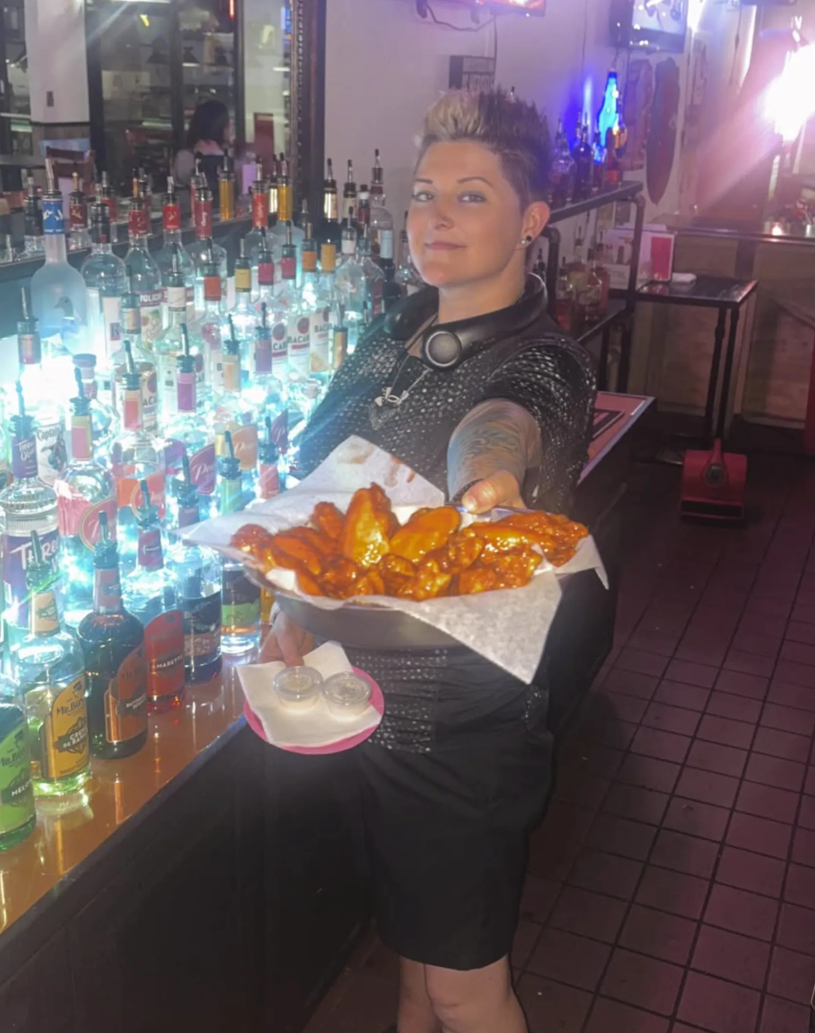 A hot order of wings being delivered to a table.